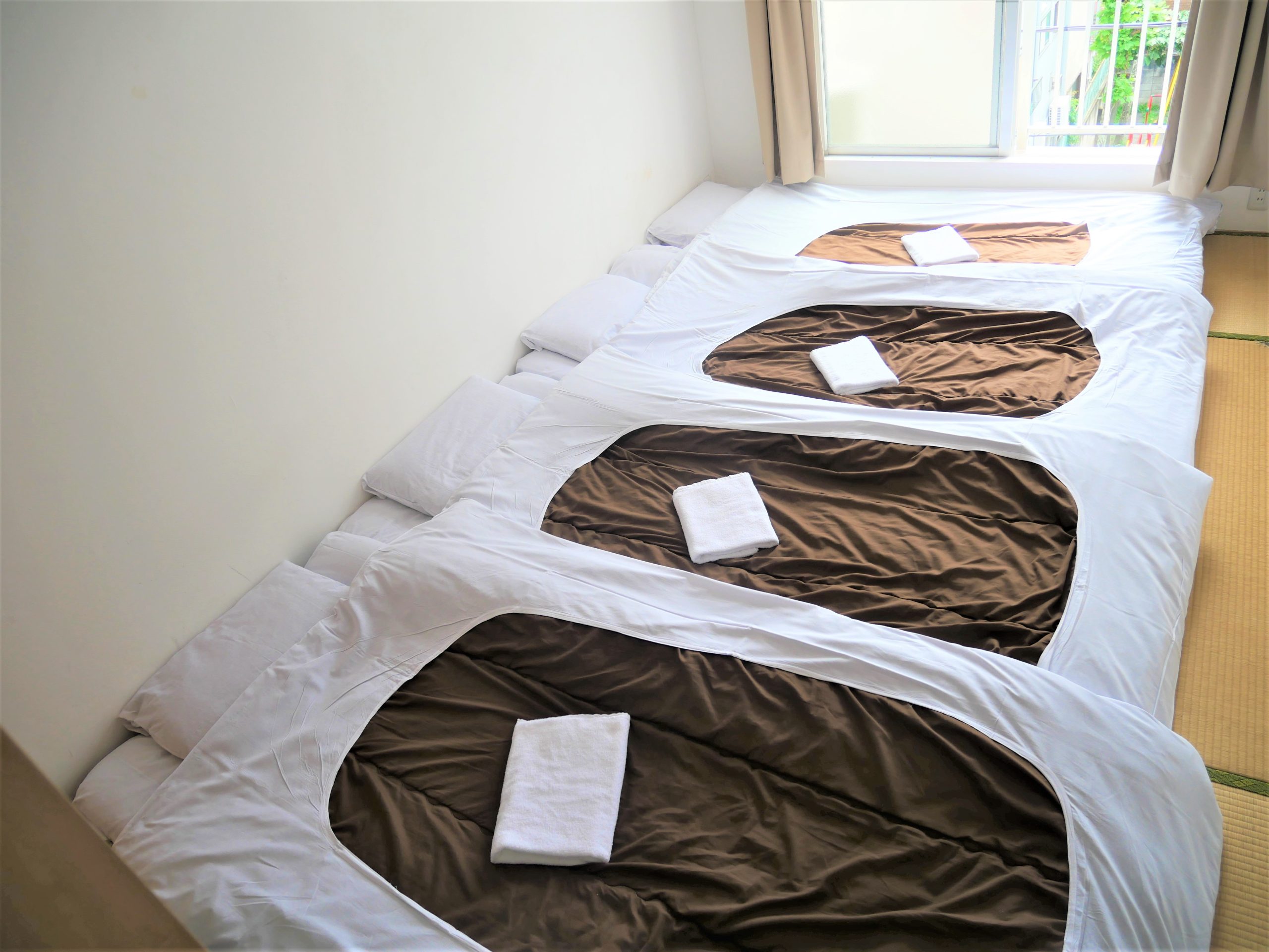 "Japanese Style Quad Room with tatami flooring and futons, ideal for families and groups at Sakura Hotel Nippori in Tokyo"